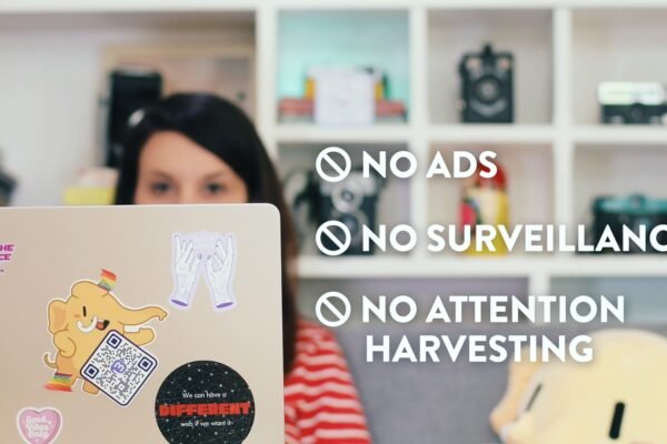 A woman with dark hair sits behind a laptop. The words “NO ADS,” “NO SURVEILLANCE,” and “NO ATTENTION HARVESTING” are overlaid on the image